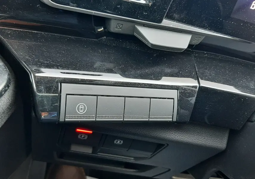 Gros plan sur les commandes noires du tableau de bord côté gauche du Renault Austral E-Tech hybride 2025, avec témoin rouge allumé.