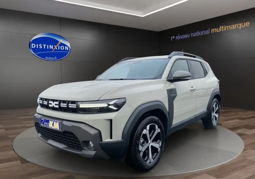 Dacia Duster beige en 3/4 avant droit, avec calandre distinctive et jantes alliage bicolores.