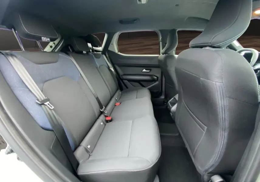 Vue intérieure montrant la banquette arrière noire et grise du Dacia Duster 2025, côté gauche, avec appuie-têtes et ceintures.