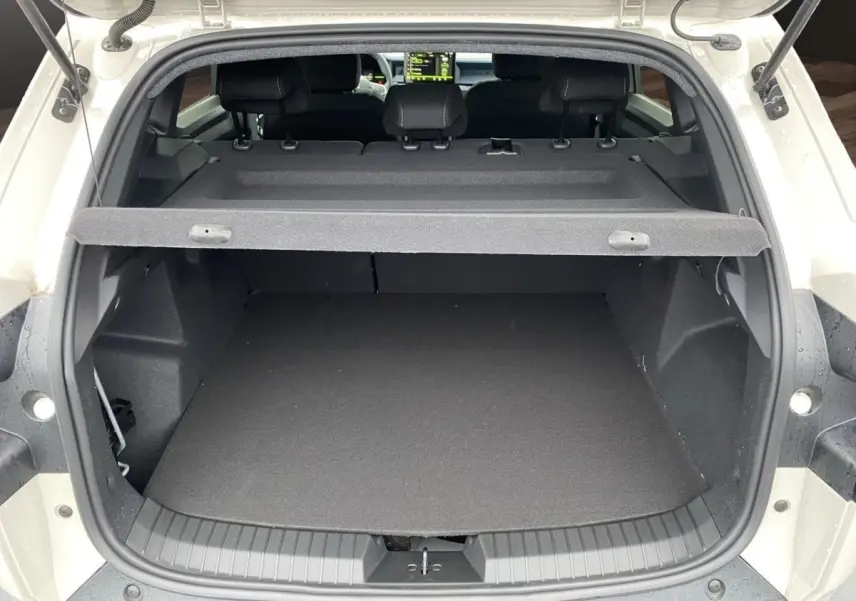 Coffre ouvert vu de l'arrière d'un Dacia Duster beige 2025, avec tablette de coffre et banquette arrière visible.