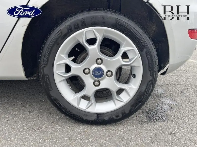 Gros plan sur la roue avant droite avec jante alu argentée d'une Ford Fiesta gris lunaire de 2012.