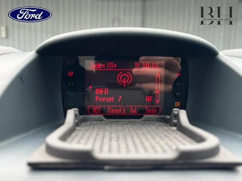 Affichage central de la radio FM en rouge sur le tableau de bord de la Ford Fiesta 2012, vue de face rapprochée.