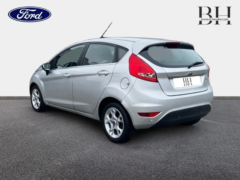 Vue 3/4 arrière droite d'une Ford Fiesta gris lunaire 5 portes avec jantes alu et becquet arrière.