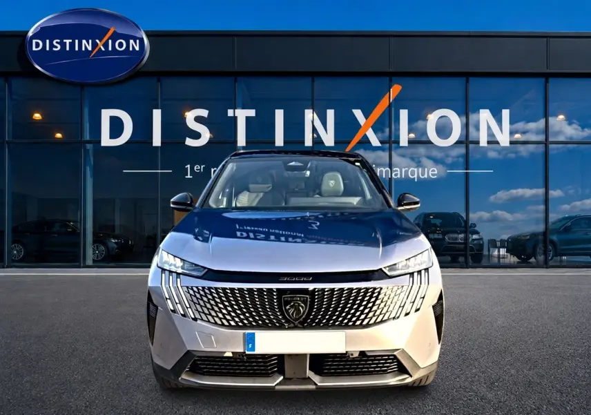 Vue frontale du Peugeot 3008 gris 2025 avec calandre distinctive et phares LED fins devant un showroom Distinxion.