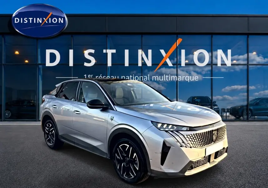 Peugeot 3008 gris en 3/4 avant droit, avec calandre distinctive et jantes alliage noires devant showroom Distinxion.