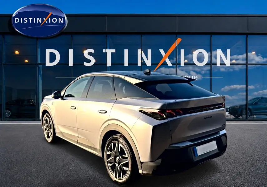 Vue 3/4 arrière droite du Peugeot 3008 gris 2025 avec jantes alu et feux arrière LED, devant une vitrine Distinxion.