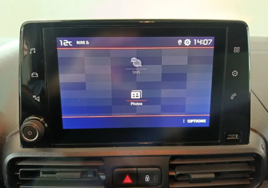Écran tactile central du tableau de bord du Citroën Berlingo blanc, affichant menu SMS et photos.