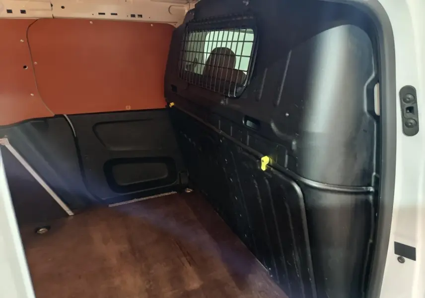 Vue intérieure côté droit du coffre blanc Citroën Berlingo 2021 avec cloison pleine noire et plancher marron.