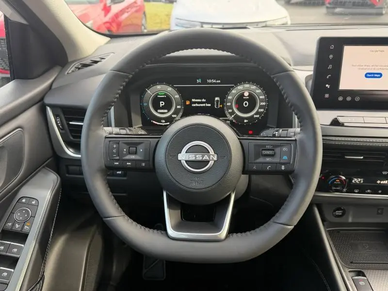 Vue intérieure centrée sur le volant Nissan du Qashqai Hybrid e-POWER 2025 avec tableau de bord numérique et écran tactile.