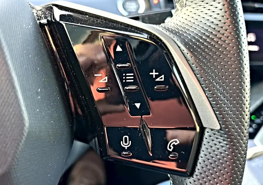 Gros plan sur les commandes vocales et téléphoniques sur le côté gauche du volant cuir perforé gris du Peugeot 3008.