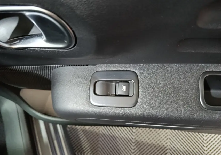 Gros plan sur le bouton de commande de la vitre électrique côté conducteur dans une Citroën C3 gris foncé, intérieur noir.