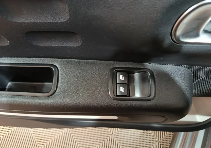 Gros plan sur les commandes de lève-vitres électriques côté conducteur de la Citroën C3 2024 gris foncé.