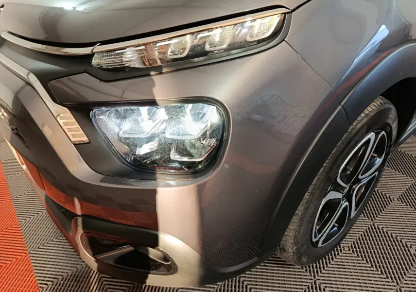 Gros plan 3/4 avant droit sur le phare LED et la roue alliage d'une Citroën C3 gris foncé 2024.