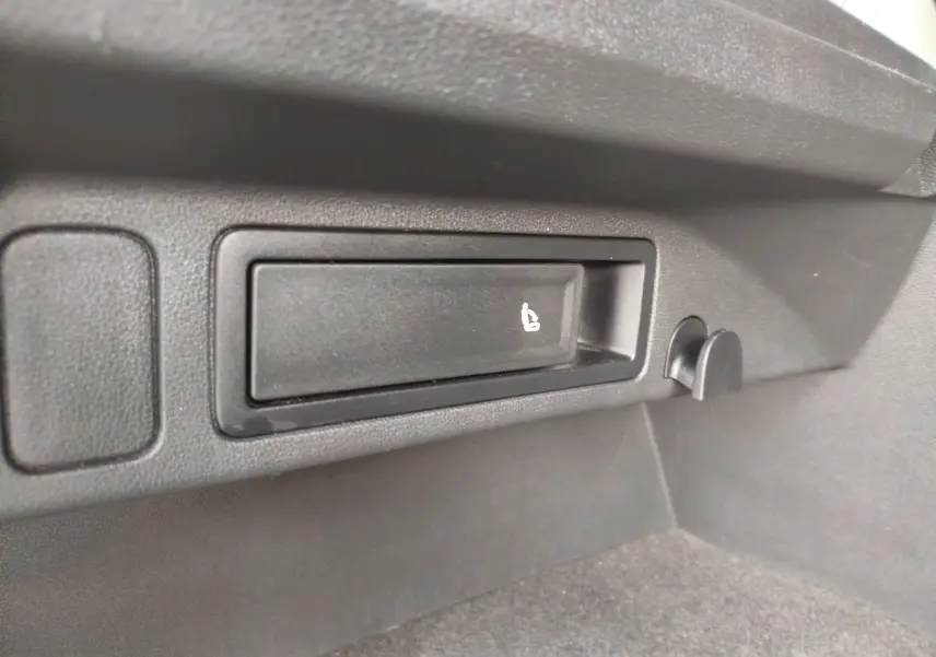 Détail du coffre du Volkswagen Tiguan noir, montrant le levier de rabattement des sièges arrière côté droit.