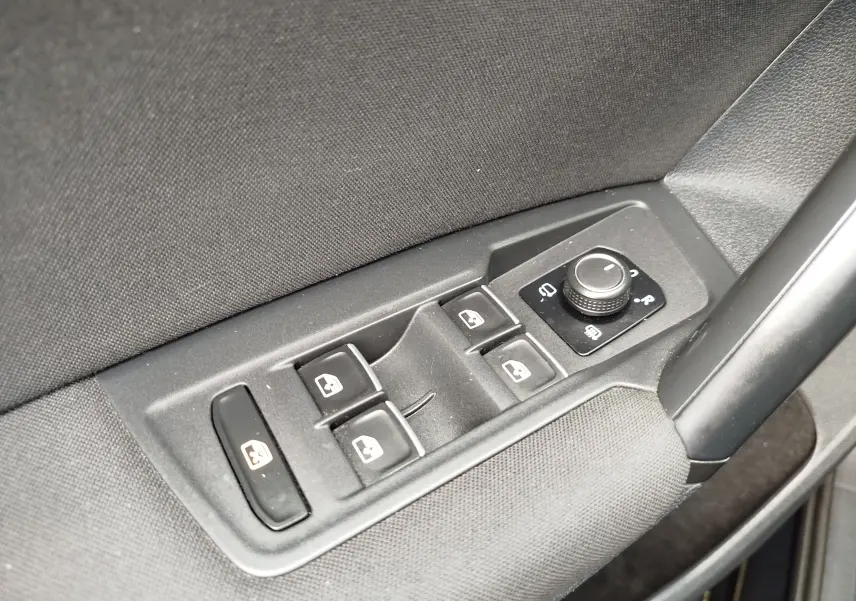 Gros plan sur les commandes de lève-vitres et réglage des rétroviseurs côté conducteur d’un Volkswagen Tiguan noir 2019.