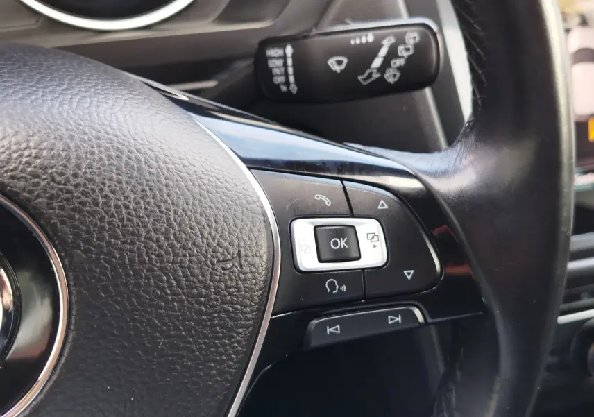 Gros plan sur les commandes multifonctions à droite du volant noir du Volkswagen Tiguan 2019, avec levier de commande en arrière-plan.