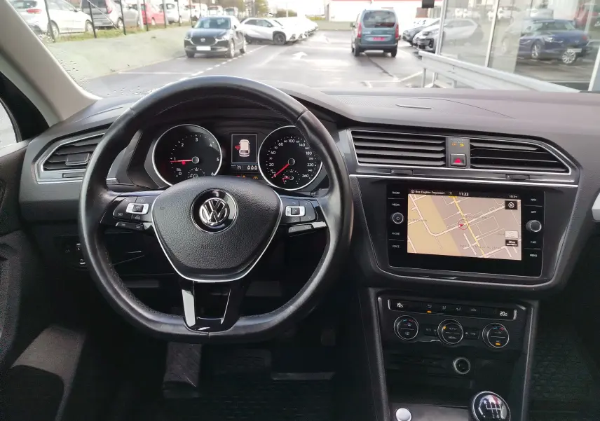 Vue intérieure centrée sur le volant et le tableau de bord du Volkswagen Tiguan 2019 avec écran GPS et boîte manuelle.