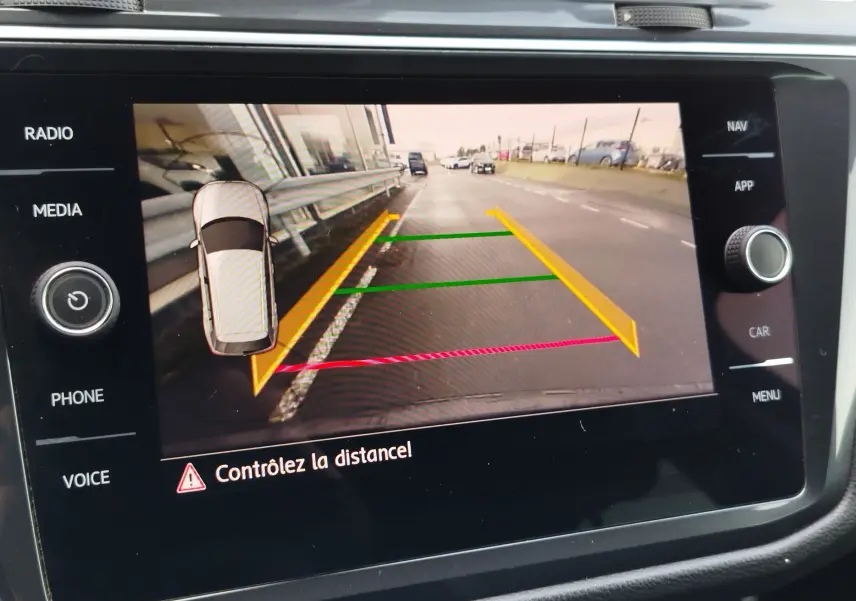 Écran de caméra de recul du Volkswagen Tiguan noir, affichant les lignes de guidage colorées et l'alerte de distance.