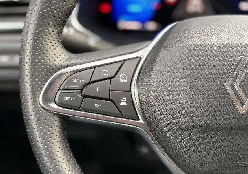 Gros plan sur le côté gauche du volant perforé gris du Renault Symbioz 2025 avec commandes de régulateur de vitesse.