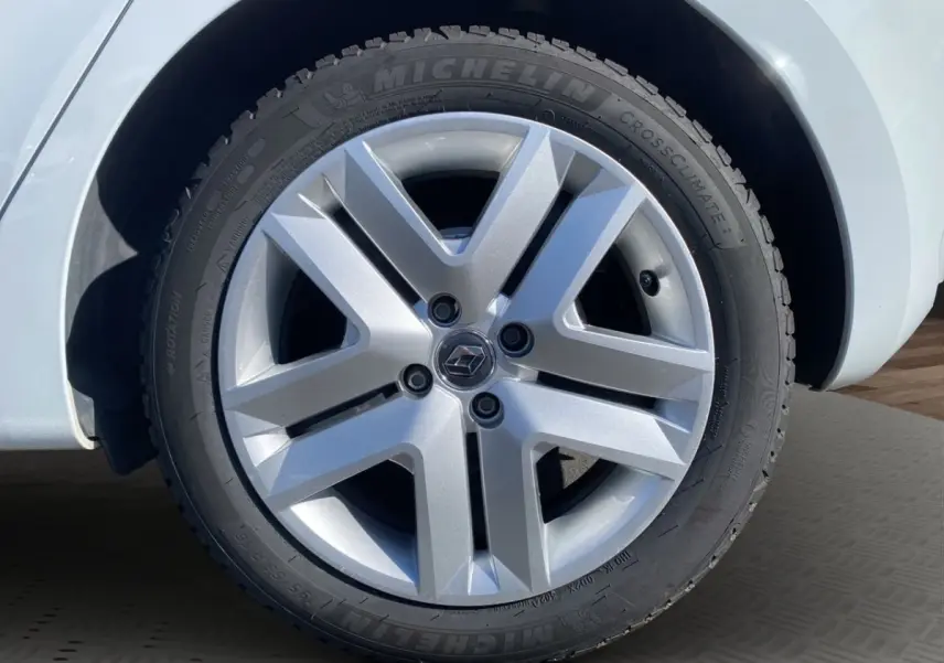 Gros plan sur la roue avant gauche d'une Renault Clio blanche avec jante alliage et pneu Michelin CrossClimate.