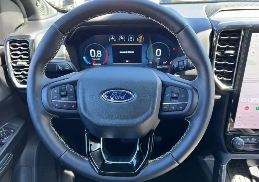 Vue rapprochée du volant cuir multifonctions noir avec logo Ford et tableau de bord numérique du Ford Ranger 2025.