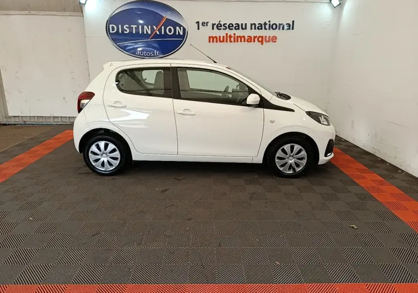 Profil droit d'une Peugeot 108 blanche VTI 72 S&S Active, compacte et citadine, dans un showroom intérieur.