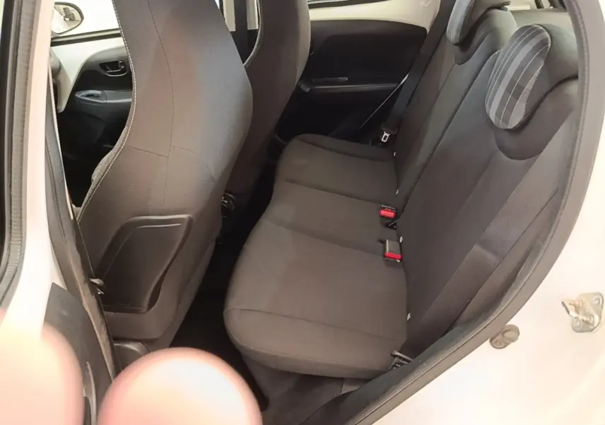 Vue intérieure côté droit montrant la banquette arrière noire et la portière ouverte d'une Peugeot 108 blanche.