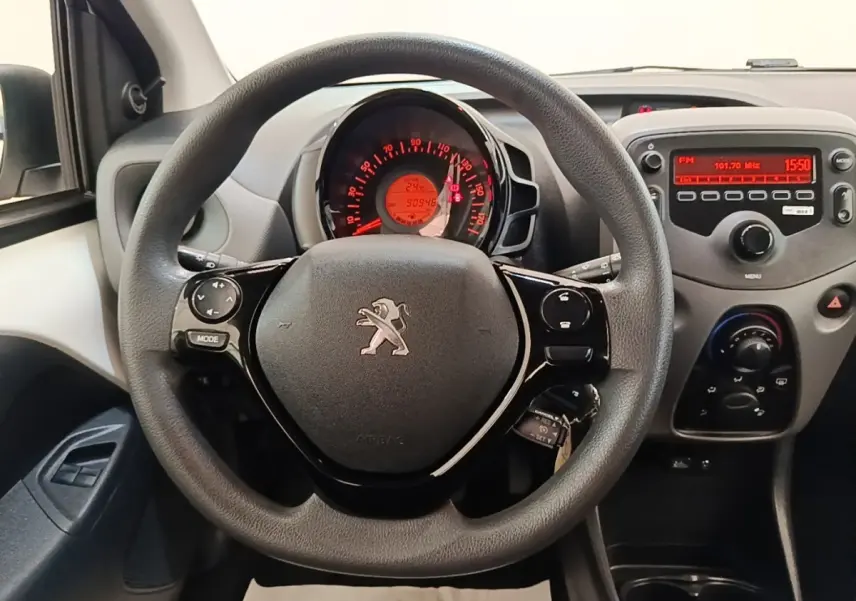 Vue intérieure centrée sur le volant multi-fonctions noir de la Peugeot 108 blanche avec tableau de bord et console radio.