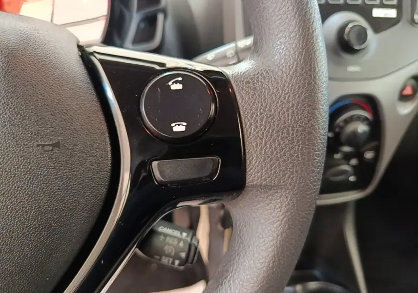 Gros plan sur le volant multifonctions noir et gris de la Peugeot 108 VTI 72 S&S Active avec commandes d’appel intégrées.