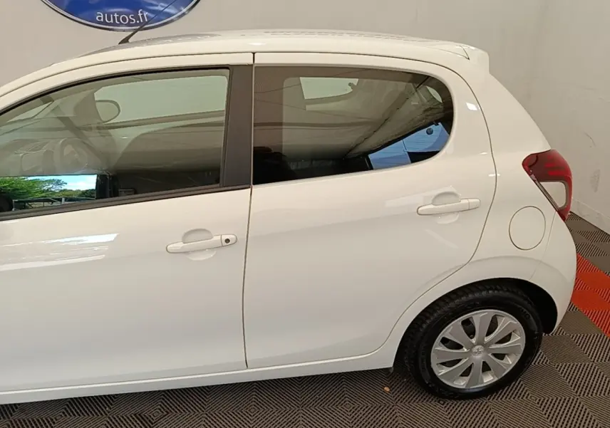 Profil droit d'une Peugeot 108 blanche de 2020, montrant les portières et la roue arrière sur sol intérieur.