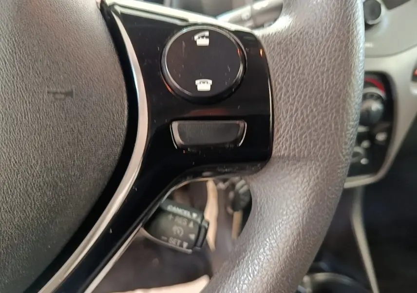 Gros plan sur le volant multifonctions gris de la Peugeot 108 blanc, avec commandes intégrées visibles.