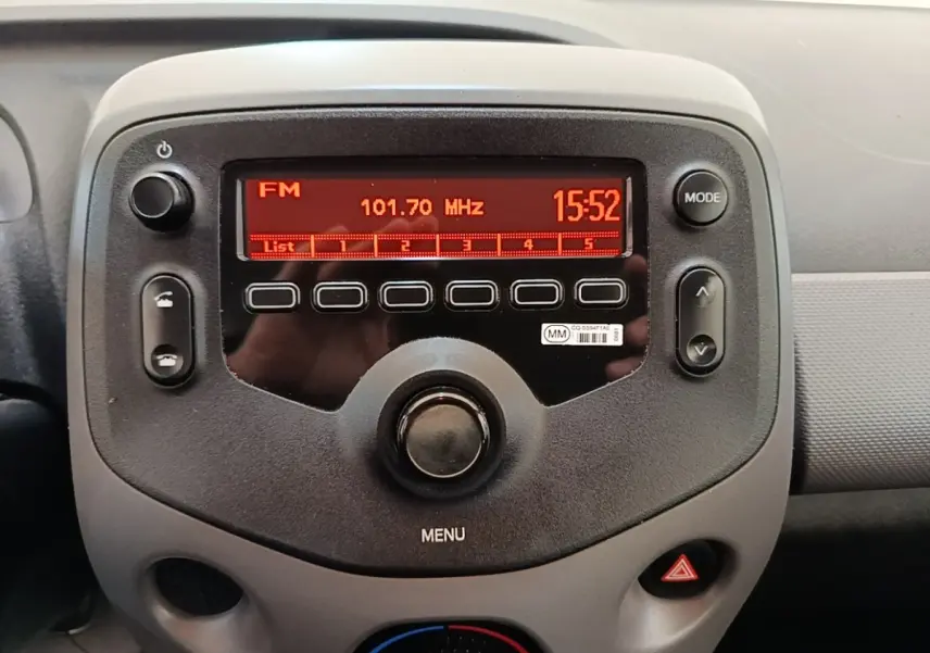 Vue rapprochée de la console centrale de la Peugeot 108 blanche, affichant la radio FM et les commandes multimédia.