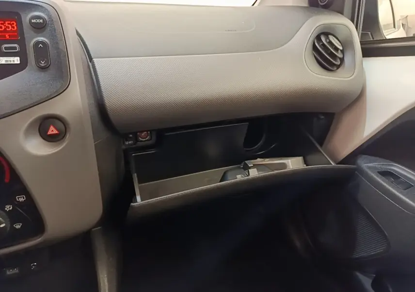 Vue intérieure côté passager du tableau de bord gris clair et boîte à gants ouverte d'une Peugeot 108 blanche de 2020.