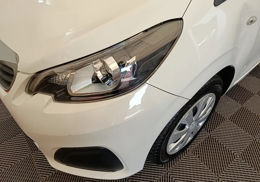 Gros plan sur l'avant droit blanc d'une Peugeot 108 VTI 72 S&S Active, mettant en valeur le phare et la roue.