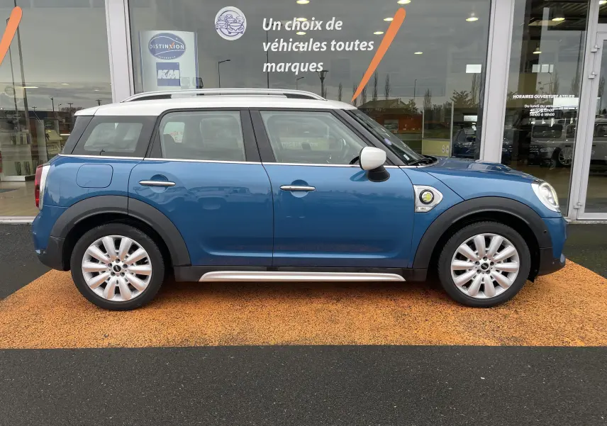Profil côté gauche d'une MINI Countryman Cooper S hybride bleu Island Metal avec toit blanc et jantes argentées.