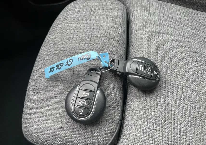 Gros plan sur deux clés MINI posées sur un accoudoir en tissu gris à l'intérieur du MINI Countryman hybride.