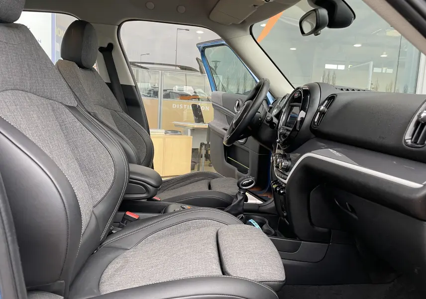 Intérieur avant du MINI Countryman hybride 2019 avec sièges tissu gris et cuir noir, volant et tableau de bord visibles.