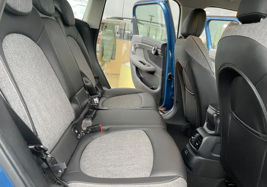 Vue intérieure côté droit des sièges arrière en tissu gris et cuir noir d'une MINI Countryman Cooper S bleu Island Metal avec porte ouverte.