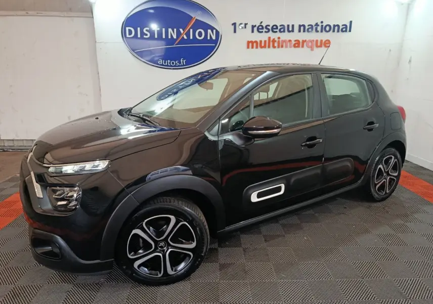 Citroën C3 BlueHDi 100 BVM PLUS noire vue 3/4 avant droit avec jantes spécifiques et protections latérales blanches.