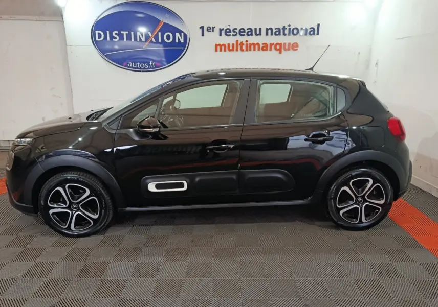 Profil latéral gauche d'une Citroën C3 noire 2024 avec protections latérales blanches et jantes stylisées.