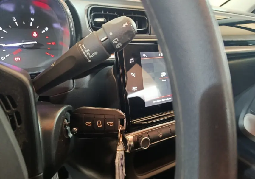 Vue rapprochée du tableau de bord et volant noir de la Citroën C3 2024 avec écran tactile et clé insérée.