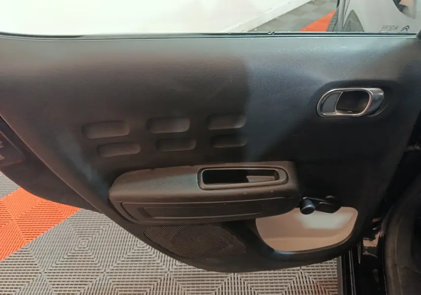 Vue intérieure de la porte arrière gauche noire de la Citroën C3 2024 avec poignée intégrée et manivelle de vitre.