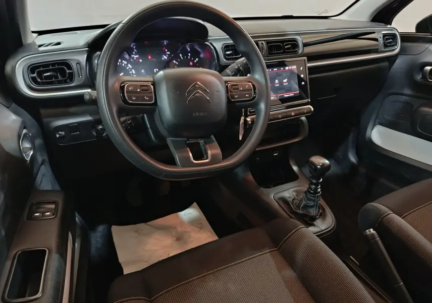 Vue intérieure côté conducteur de la Citroën C3 2024 noire, volant multifonctions et écran tactile central visible.