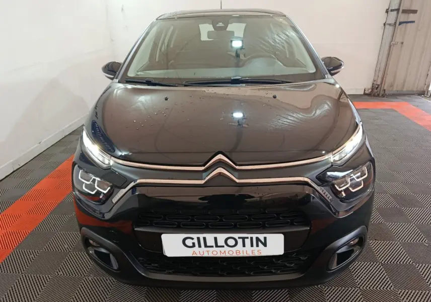 Vue avant d'une Citroën C3 noire 2024 avec phares LED et calandre chromée dans un garage.