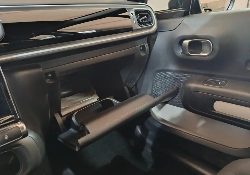Vue intérieure côté passager de la Citroën C3 2024 noire, avec boîte à gants ouverte et tableau de bord noir brillant.