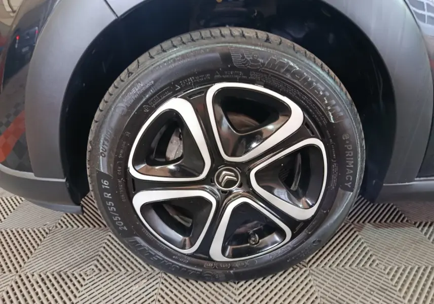Gros plan sur la roue avant gauche noire d'une Citroën C3 2024 avec jante alliage bicolore et pneu Michelin.