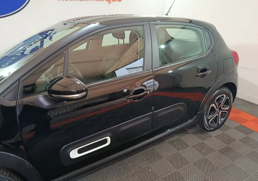 Profil côté gauche d'une Citroën C3 noire 2024 avec protections latérales blanches et jantes stylisées.