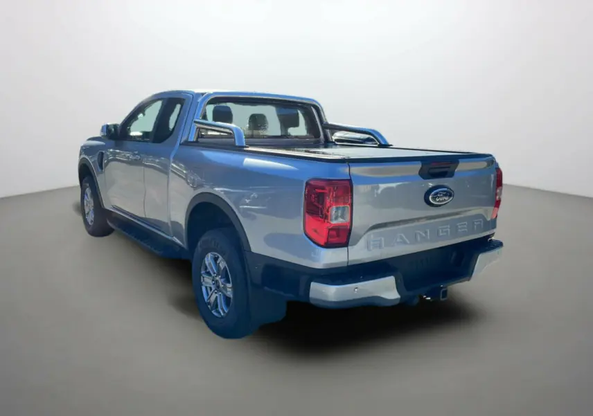 Ford Ranger gris iconic en 3/4 arrière droit avec arceaux inox et rideau coulissant de benne visible.