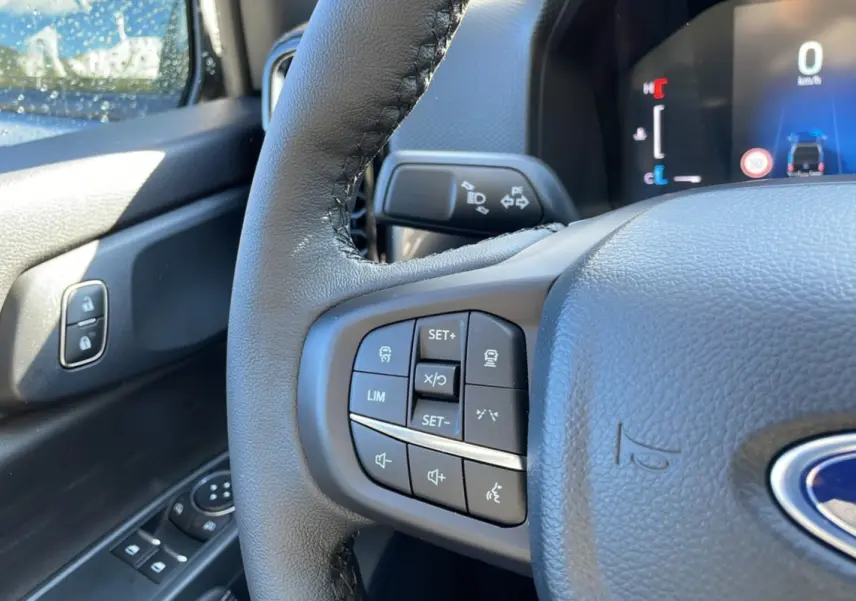 Gros plan sur le volant cuir multifonctions côté gauche du Ford Ranger gris iconic avec commandes de régulateur et audio.