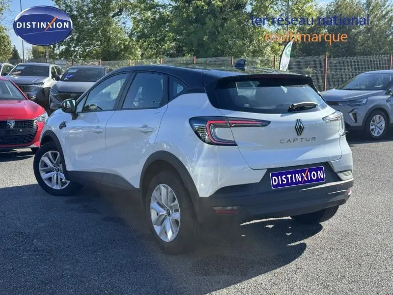 Vue 3/4 arrière droite d'un Renault Captur blanc nacré 2025 avec toit noir et feux arrière LED distinctifs.